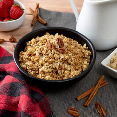 Brown sugar maple multi-grain cereal in black bowl with pecans, cinnamon, strawberries