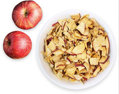 Bowl of dried apple slices and two fresh red apples on white background